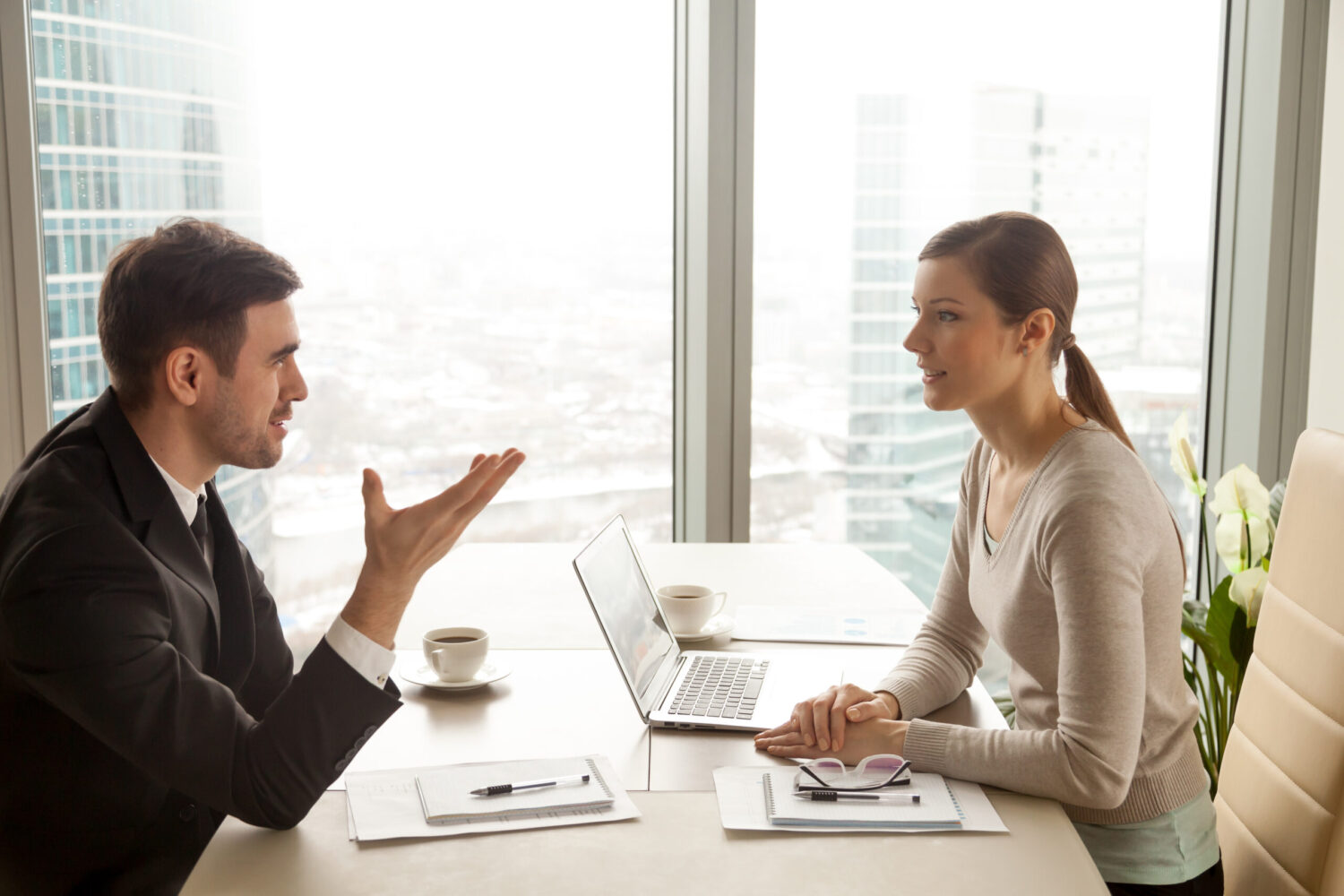 Businessman and businesswoman discussing work at office desk nea